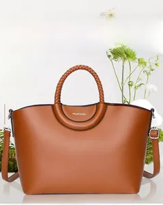 Détail d'un sac cabas marron avec poignées tressées et logo sur le cuir de qualité