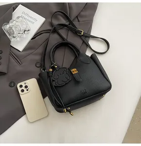 Detail of black litchi grain bucket bag with gold hardware and a cute puppy charm