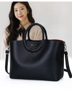 Vue détaillée d'un sac cabas en cuir noir avec des poignées circulaires tressées à la main