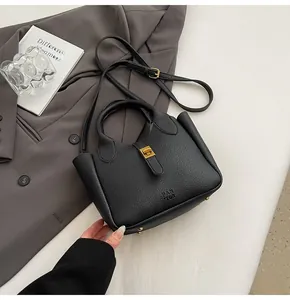 Detailed macro of black lychee grain leather handbag with gold metal twist lock and branding