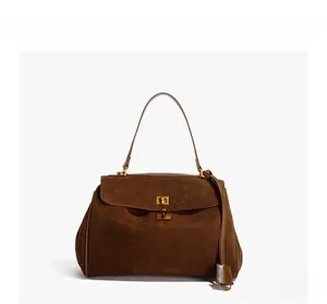 Detail of dark brown suede handbag featuring a gold-tone twist lock and rounded silhouette
