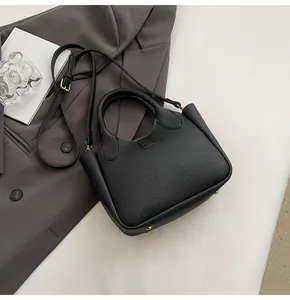 Close-up of black lychee texture leather bucket bag with gold metal feet and adjustable strap