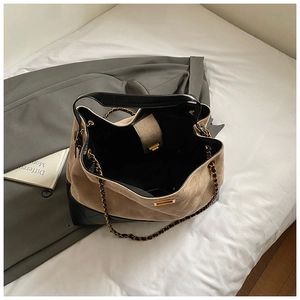 Detailed close-up of the beige suede and black quilted leather bucket bag with chain strap