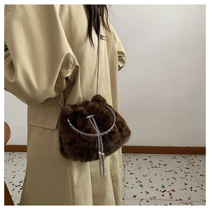 Deep brown faux fur bucket bag with silver chain strap shown worn on a trench coat