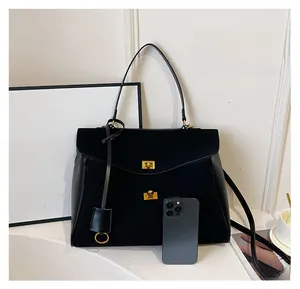 Détail du sac cabas noir avec fermoir doré et smartphone pour comparer la taille