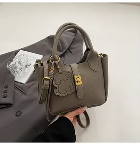 Detail of grey lychee leather bucket bag with gold twist lock and cute puppy charm