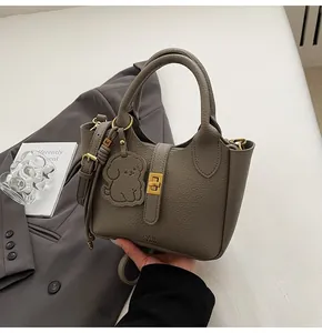 Close-up of grey litchi texture handbag with gold twist lock and cute dog charm pendant