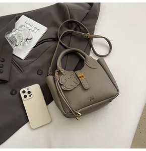 Detail of taupe lychee leather bucket bag with gold clasp and cute bear charm