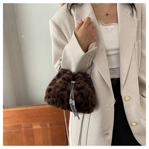 Detailed close-up of leopard print faux fur bucket bag with metal chain and tassels