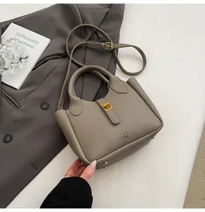 Detail of taupe lychee leather bucket bag with gold hardware and protective feet