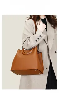 Gros plan d'un sac cabas en cuir grainé marron avec pieds de protection en métal et détails tressés