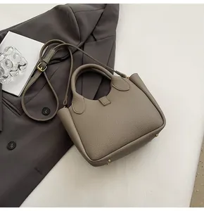 Detailed view of taupe lychee texture leather bucket bag with metal base studs