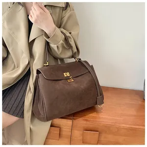 Detail of vintage coffee brown suede handbag with elegant gold twist lock and large capacity