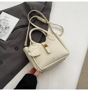 Detail of off-white lychee pattern bucket bag with dog charm on a grey suit jacket
