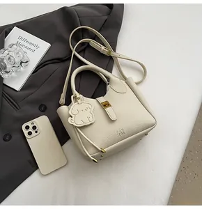 Detail of lychee pattern cream bucket bag with gold buckle and cute puppy charm