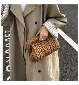 Close-up of brown cable knit cloud bag with gold chain strap on trench coat outfit