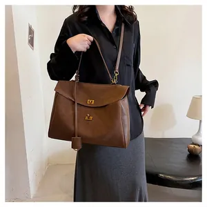 Détail d'un sac cabas en cuir marron avec fermoir rotatif doré et bandoulière réglable
