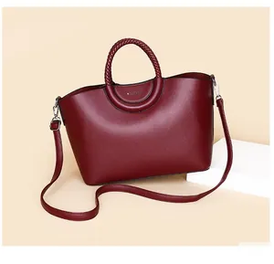 Gros plan du sac cabas bordeaux en similicuir avec poignées tressées et logo métal