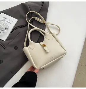 Detail of lychee pattern leather handbag with gold metal clasp and thin shoulder strap
