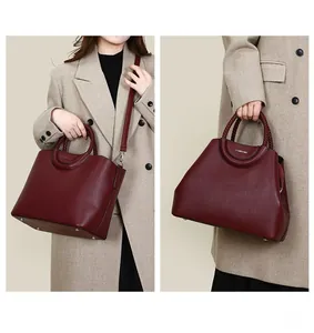 Détail du sac cabas bordeaux avec poignée tressée et texture de cuir grainé de luxe