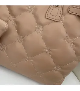 Détail de la maroquinerie matelassée beige avec broderies d'étoiles et de fleurs