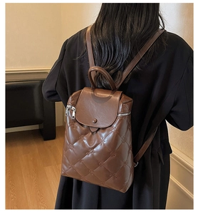 Rear view of woman wearing a brown quilted backpack with elegant floral embossing texture