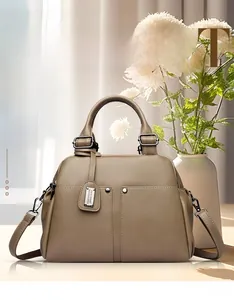 Close-up of taupe pebble leather Boston bag with silver rivets and smooth handles