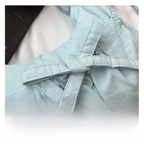 Close-up of light blue puffy crossbody bag showing pleated texture and knot detail