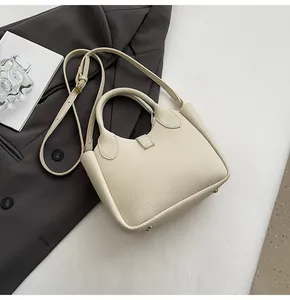 Detail view of lychee pattern leather handbag with metal base studs and adjustable strap