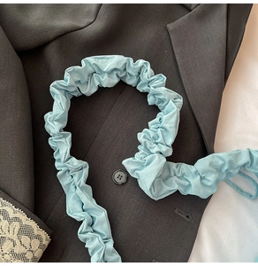 Detail showing the light blue ruched drawstring fabric texture of the nylon shoulder bag