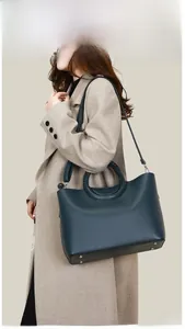 Détails du sac cabas en cuir vert foncé avec anses tressées et bandoulière réglable