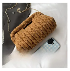 Detailed texture of brown knitted shoulder bag with elegant gold metal chain strap