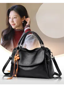 Detail of black cowhide handbag with lychee pattern and wooden bead pendant accessory