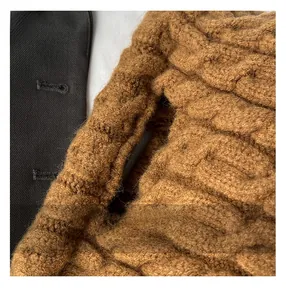 Macro detail of brown chunky knit shoulder bag with textured weave and gold chain strap
