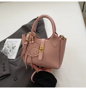 Close-up of pink lychee textured bucket bag with gold clasp and dog charm detail