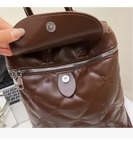 Detailed macro view of deep brown quilted leather bag with silver magnetic snap closure