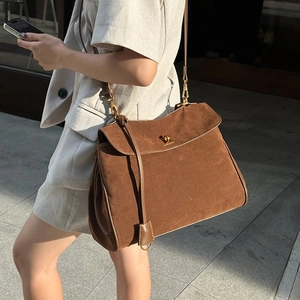 Brown frosted suede shoulder bag with vintage gold buckle in urban street setting