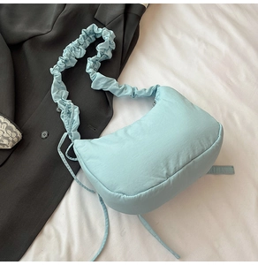 Detail of light blue pleated nylon shoulder bag with drawstring accents on fabric