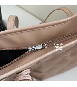 Détail de la fermeture éclair métallique et de la texture matelassée du sac beige