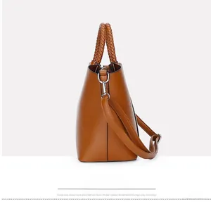 Détail d'un sac seau marron avec poignée tressée et attaches métalliques latérales