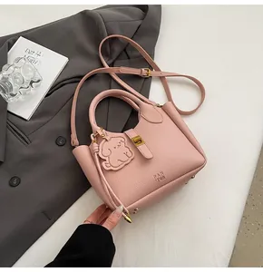 Detailed close-up of a pink litchi grain bucket bag with a cute dog leather charm