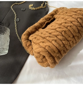Detail of brown knitted cloud bag with pleated texture and gold chain shoulder strap