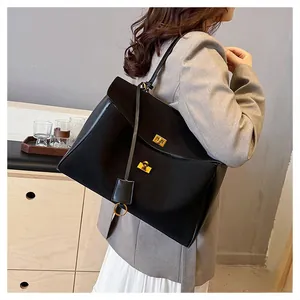 Détail du sac cabas noir avec fermoir tournant doré et texture en cuir lisse élégante