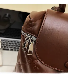 Detailed macro view of smooth metal zippers and floral quilted leather on dark brown backpack