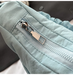 Detail of the high-quality silver metal zipper and quilted nylon fabric on light blue bag