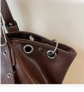 Detailed macro view of dark brown PU leather tote with silver metal grommet accents