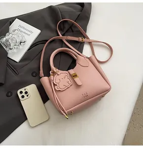 Close-up of pink litchi grain leather bucket bag with dog pendant and gold metal hardware