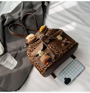 Detail of leopard print backpack with brown leather flap and gold metal buckle design