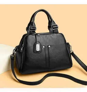 Detail of black pebbled leather Boston bag with silver hardware and adjustable strap