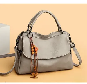 Close-up of grey litchi grain leather handbag with wooden bead pendant and metal hardware